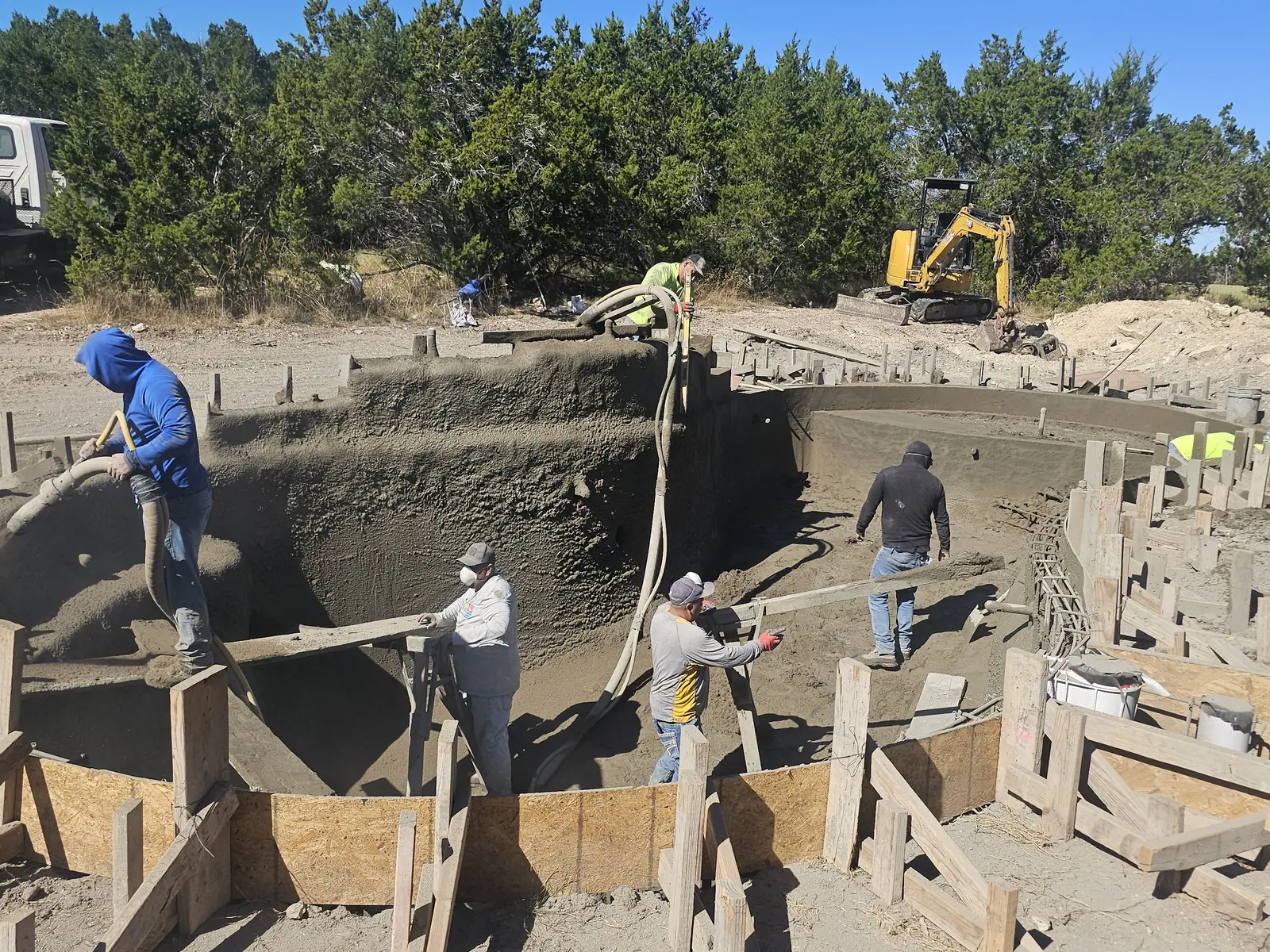 Crew spraying gunite concrete onto the steel to form the pool shell