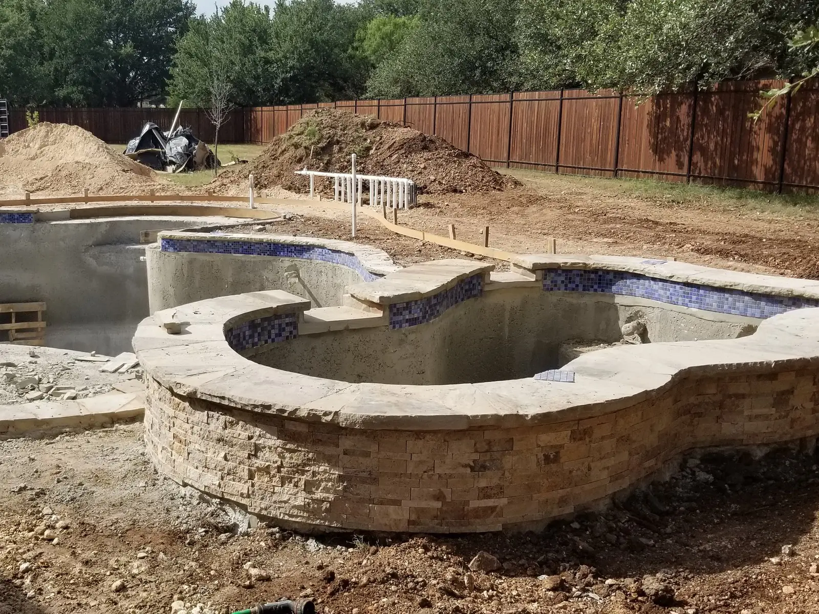 Blue waterline tile and stone coping on a freeform pool and spa