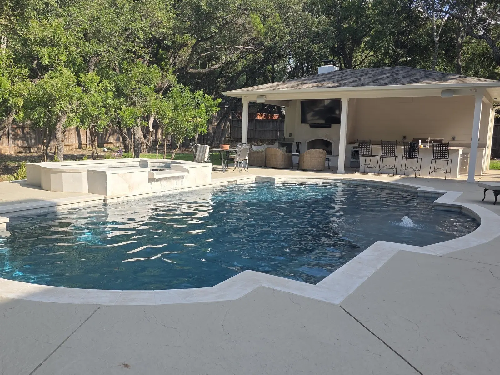 Finished pool with a raised spa beside a white pavilion