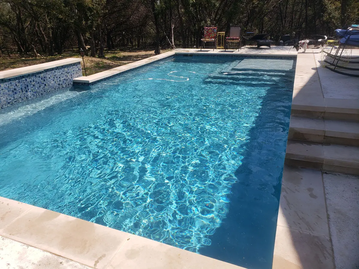 Rectangular pool with glass tile and a tanning ledge