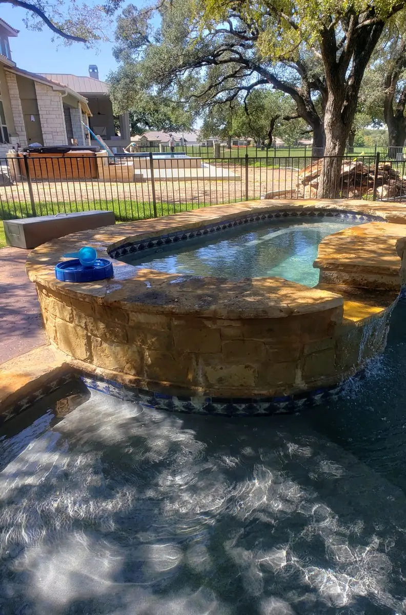 Raised stone spa spilling into a pool