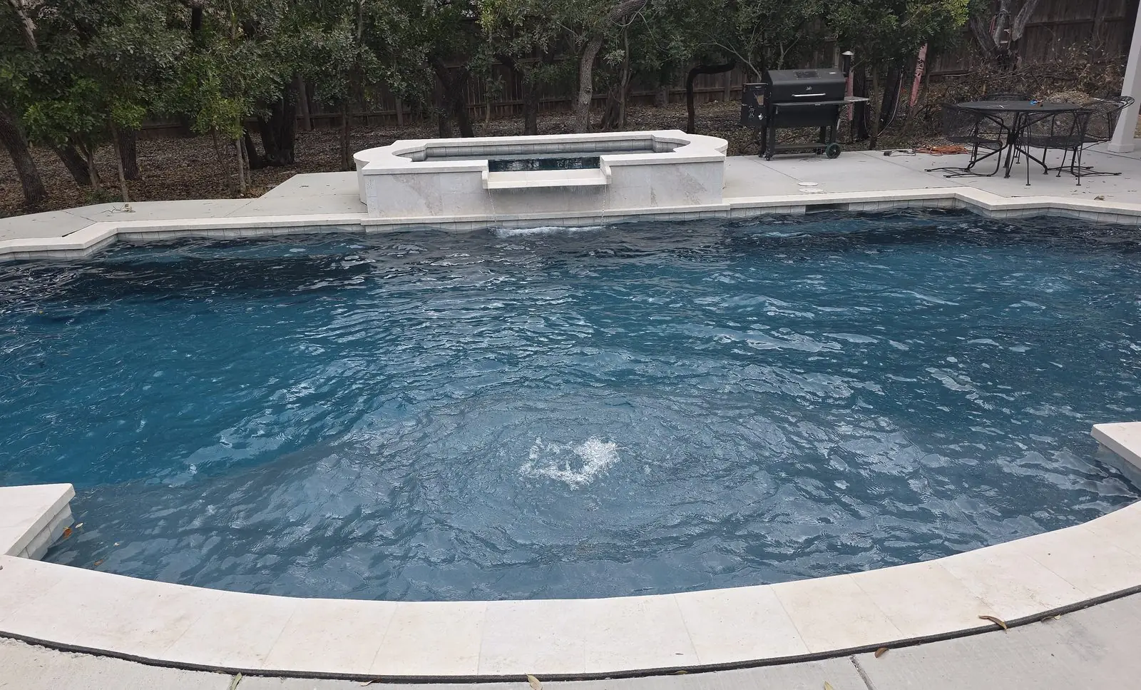 Pool with a raised spa spilling into deep blue water