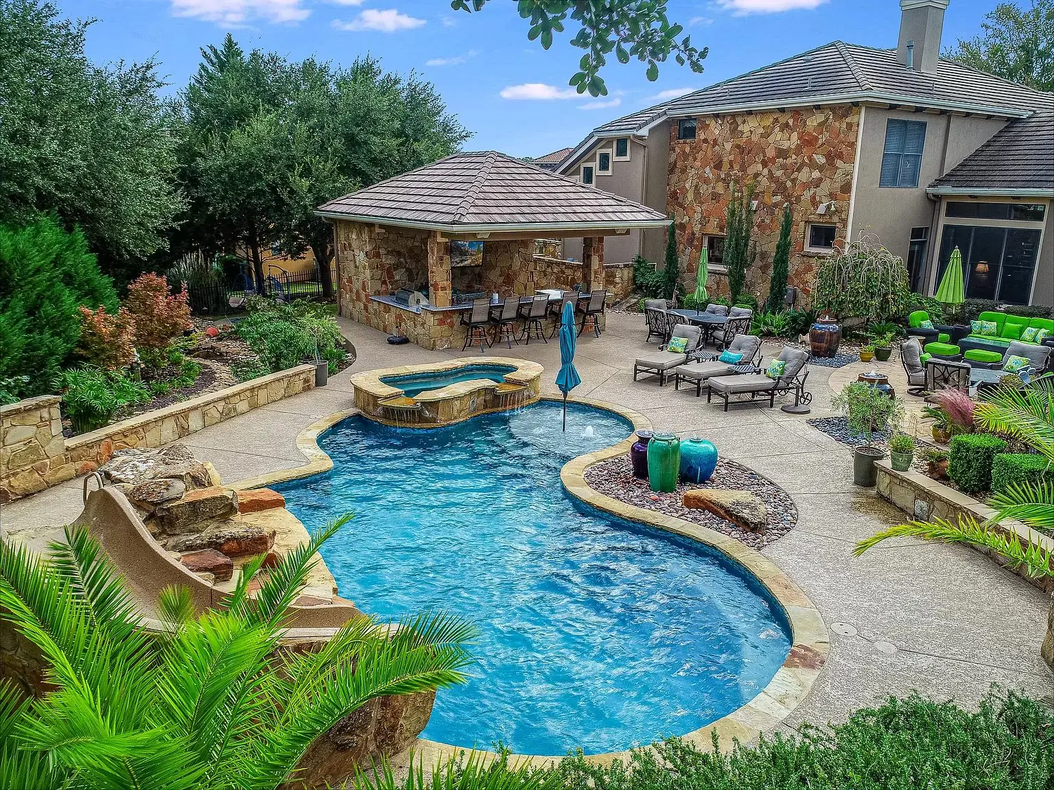 Stone cabana with a tile roof and bar seating behind a freeform pool