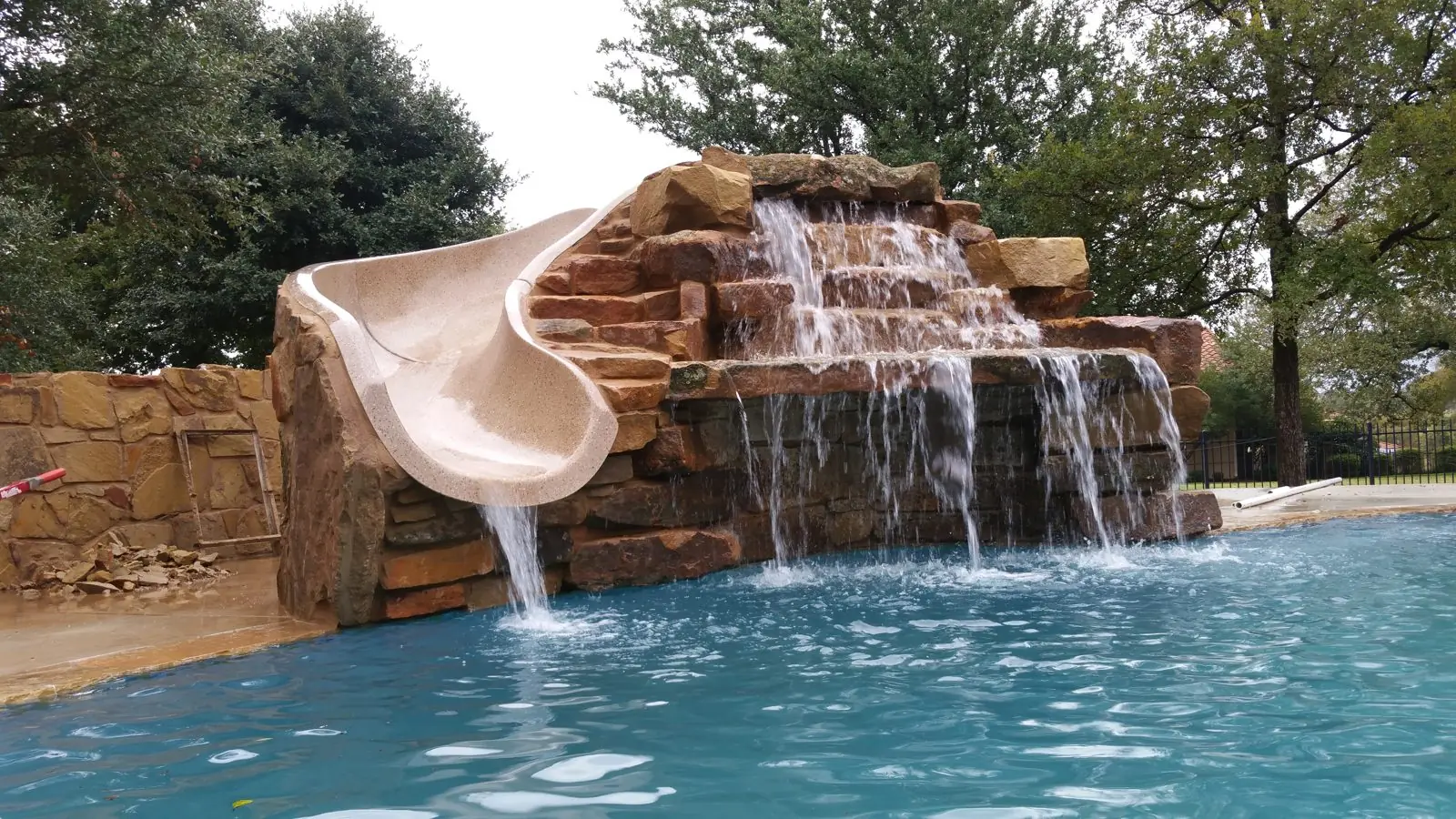 Rock waterfall and slide pouring into a pool