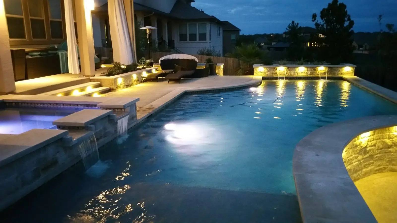 Pool at dusk with lit steps and deck lighting