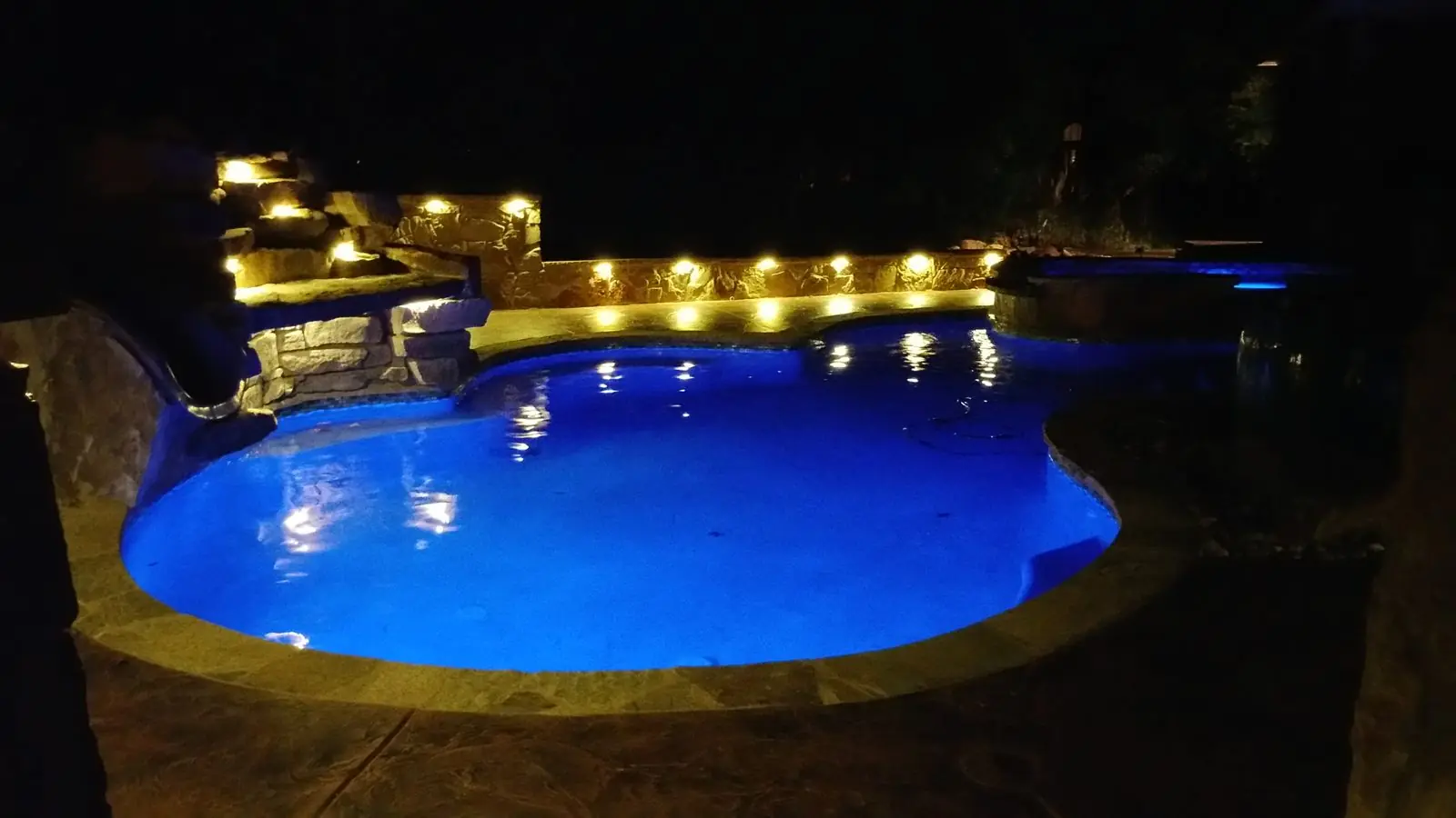 Freeform pool glowing blue at night