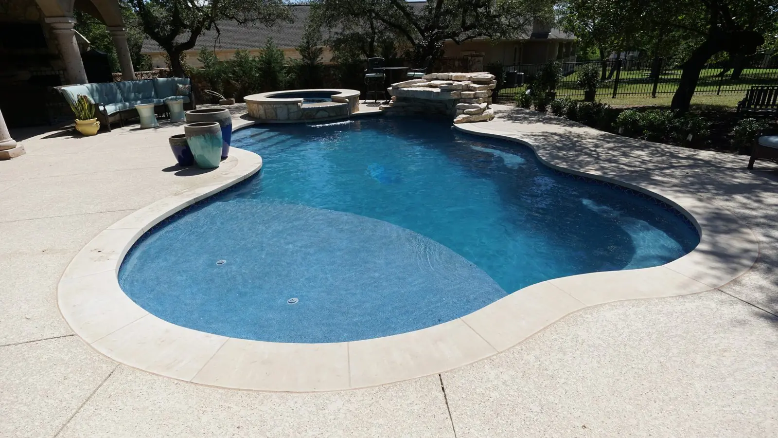 Kidney-shaped pool with a pale deck and spa