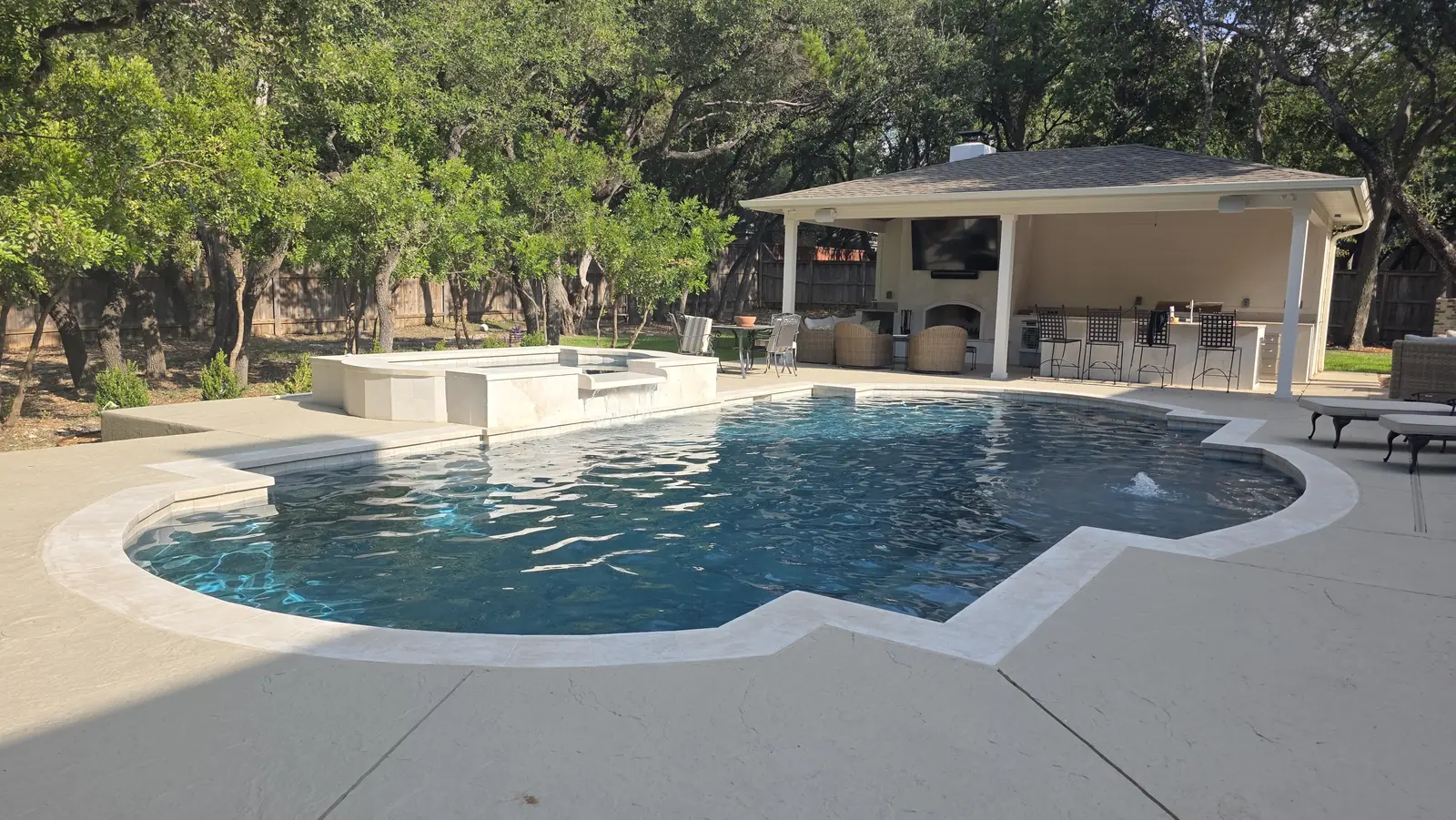 Pool with raised travertine spa and a pavilion with fireplace and bar