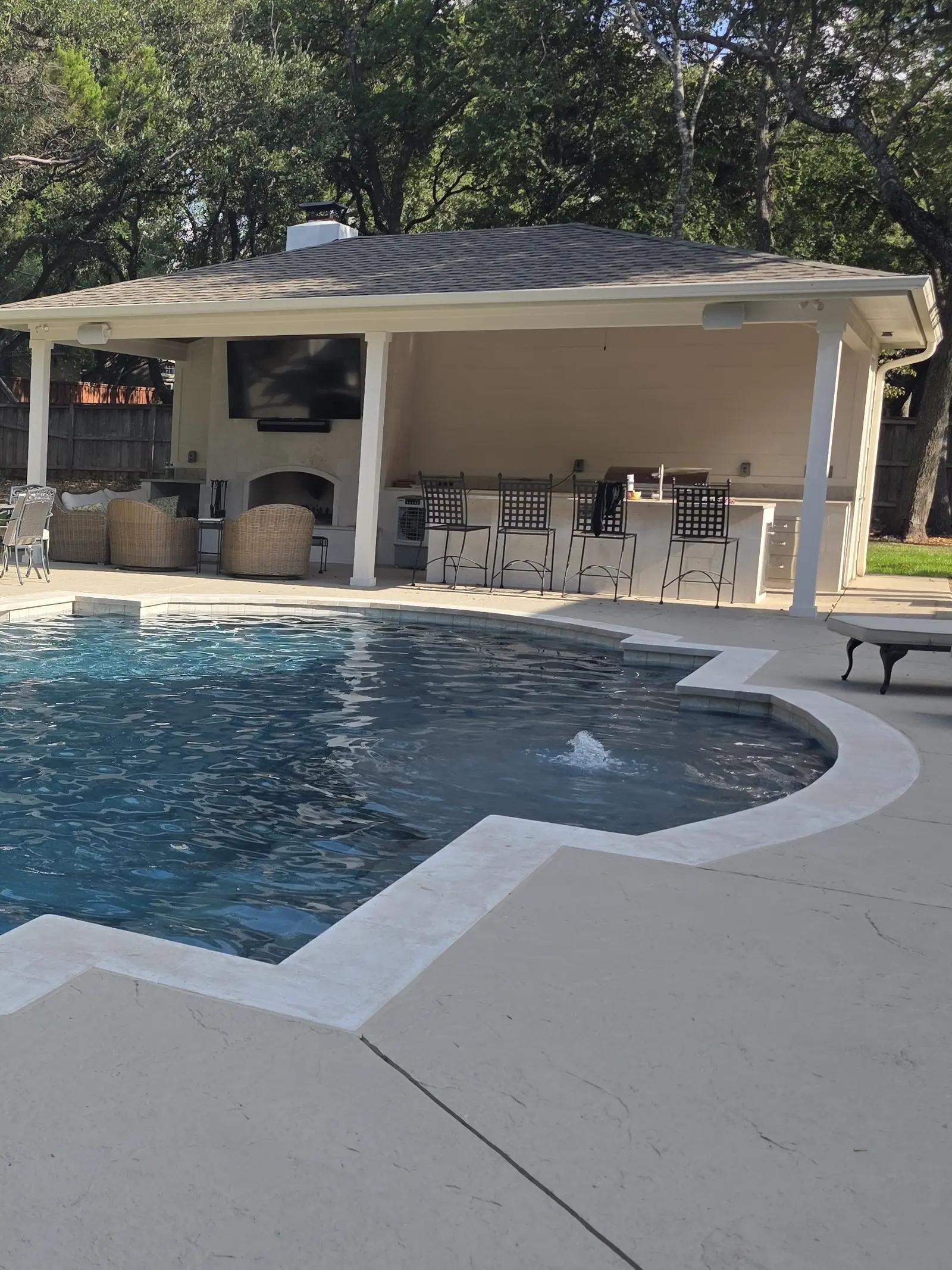 Poolside pavilion with fireplace, bar seating and lounge chairs