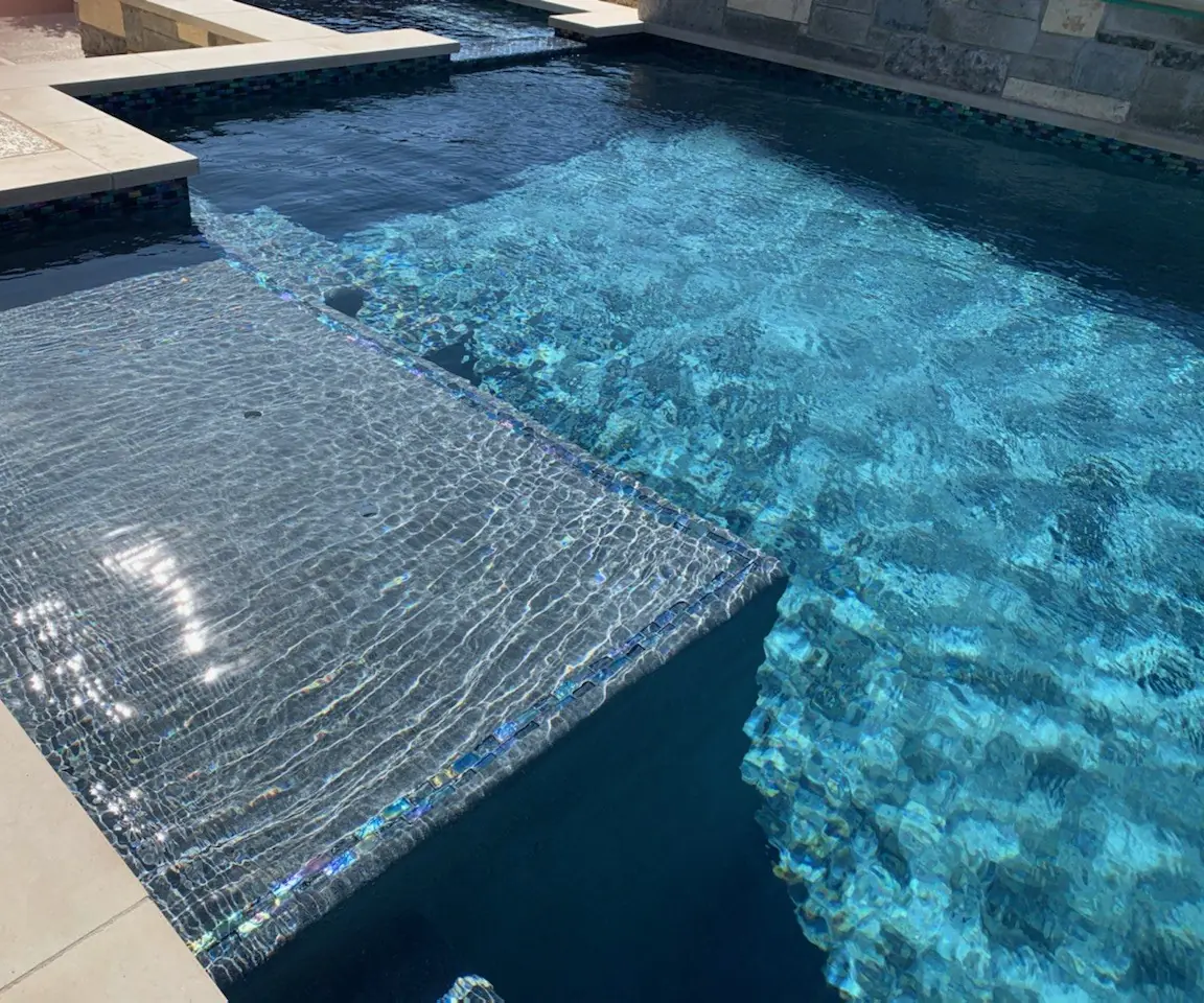 Shallow tanning ledge edged in iridescent glass tile in clear water
