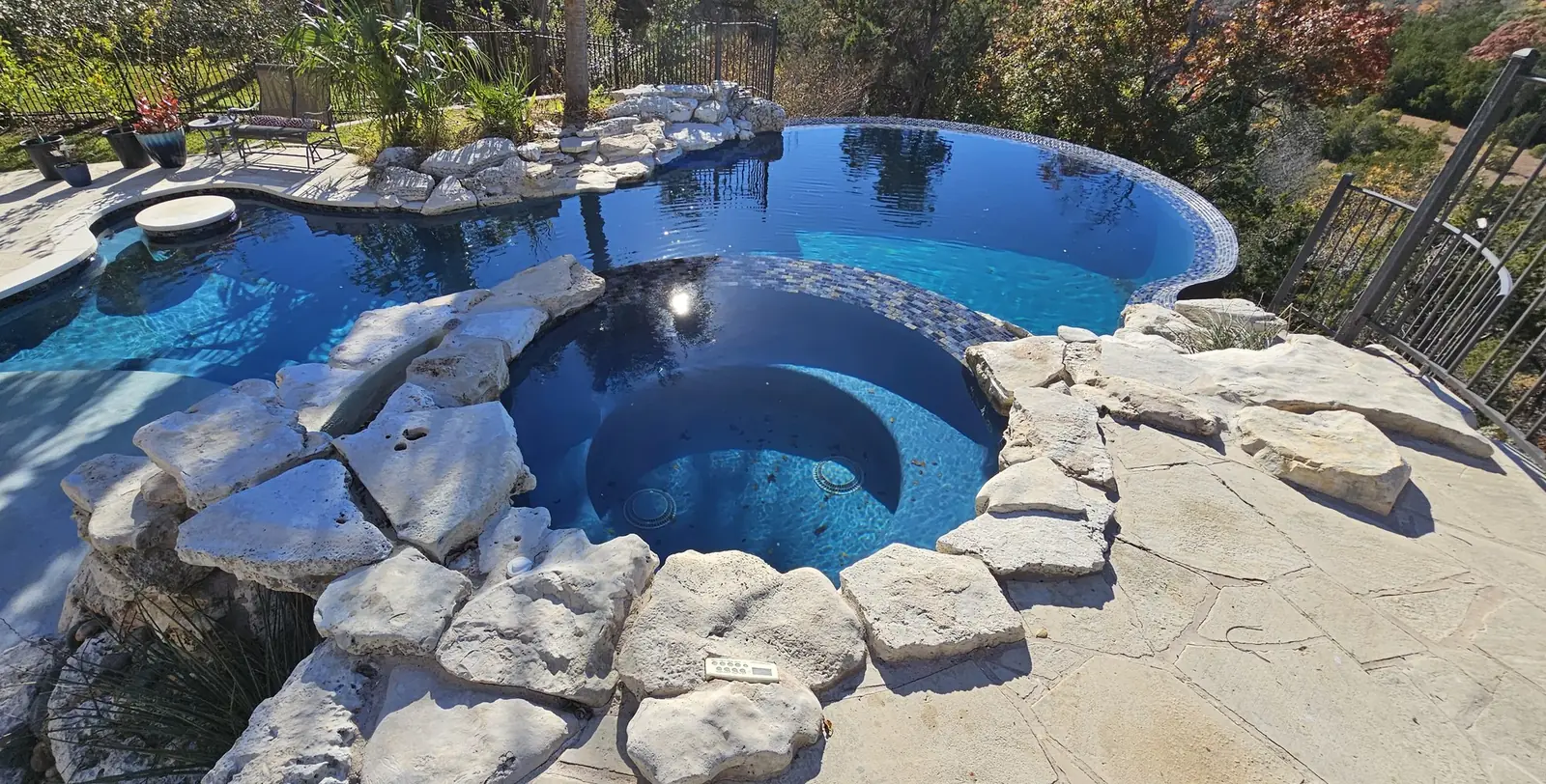 Remodeled pool and boulder-edged spa filled with deep blue water on a hillside