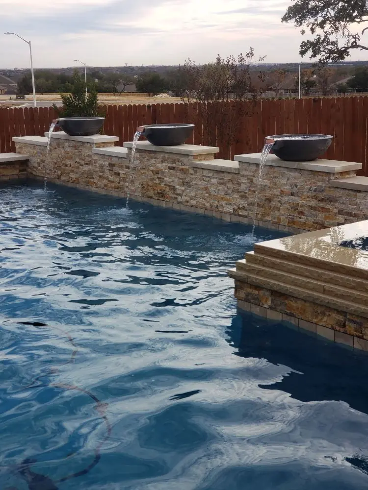 Geometric pool with a raised stone wall and water bowls