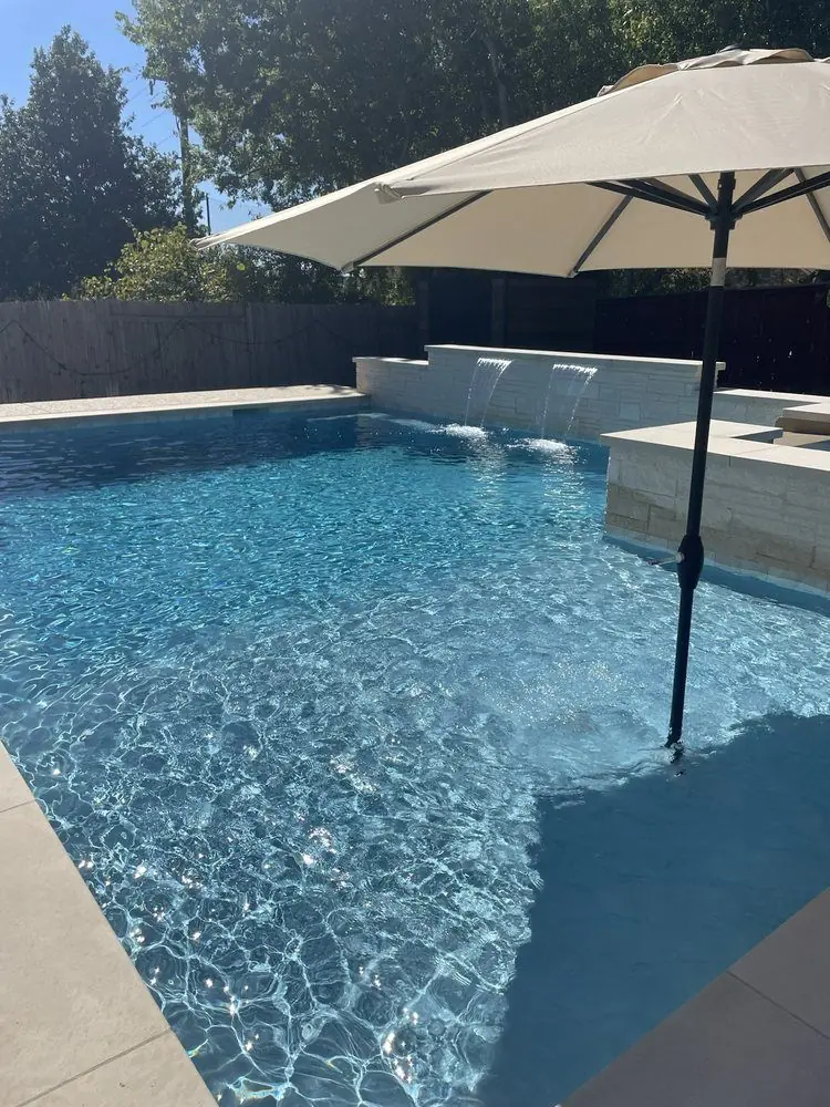 Geometric pool with clear blue water and a shade umbrella on the deck